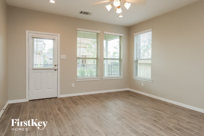 an empty living room with a white door and three windows