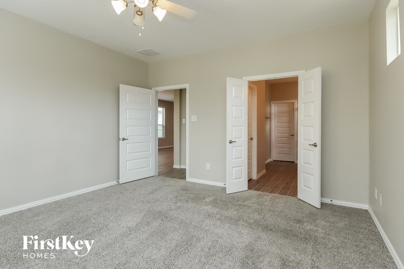 an empty living room with three doors and a ceiling fan