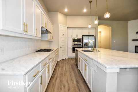 A kitchen with white cabinets and a marble countertop.