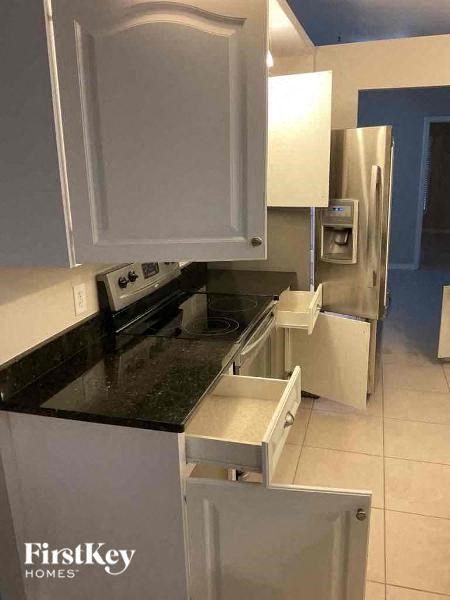 A kitchen with a black counter top and white cabinets.