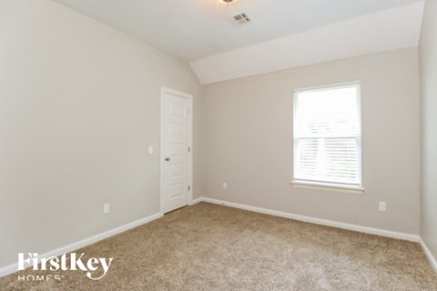 a bedroom with carpet and a white door and window
