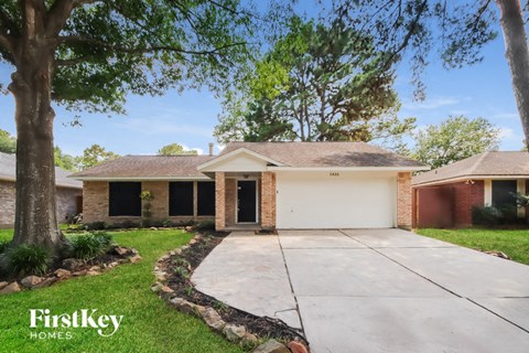 a small brick house with a driveway and a tree
