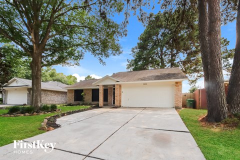 a house with a driveway and trees in front of it