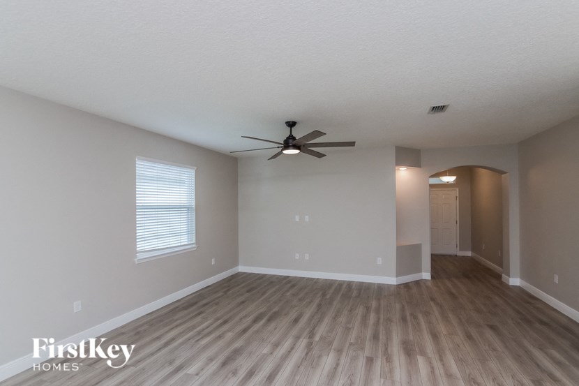 an empty living room with a ceiling fan and wood floors