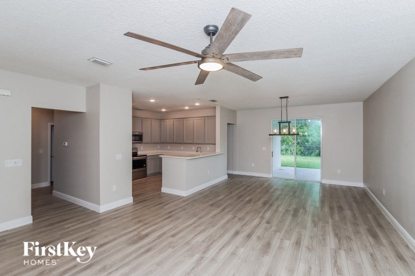an empty living room and kitchen with a ceiling fan
