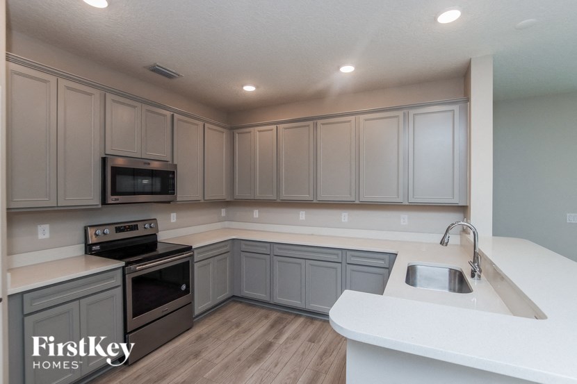 a kitchen with white counter tops and gray cabinets