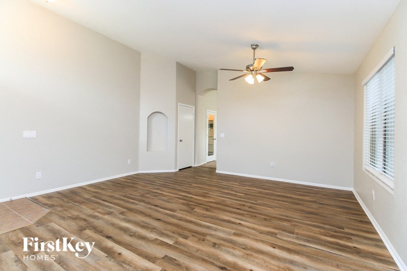 A spacious room with wooden flooring and a ceiling fan.