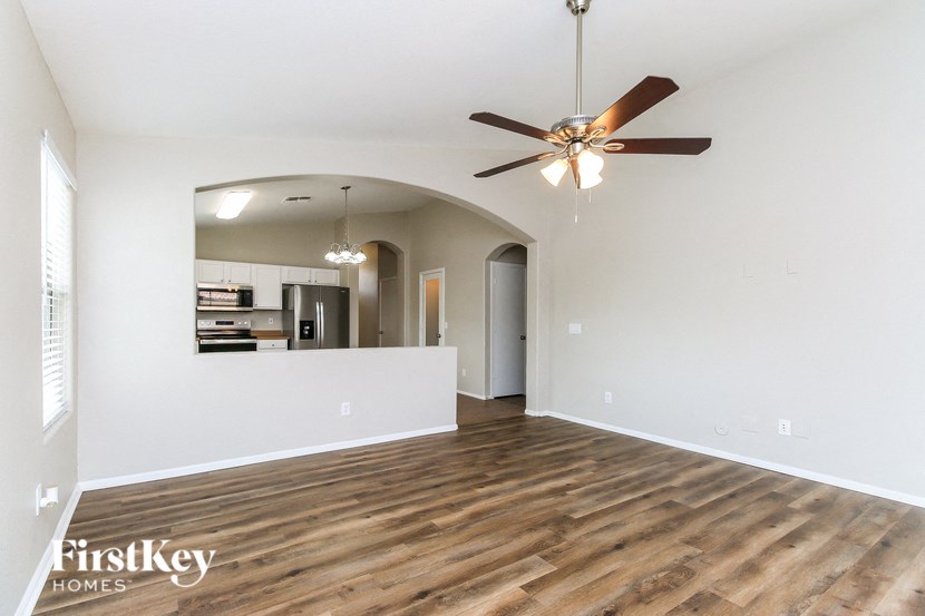 A spacious room with a wood floor and a ceiling fan.
