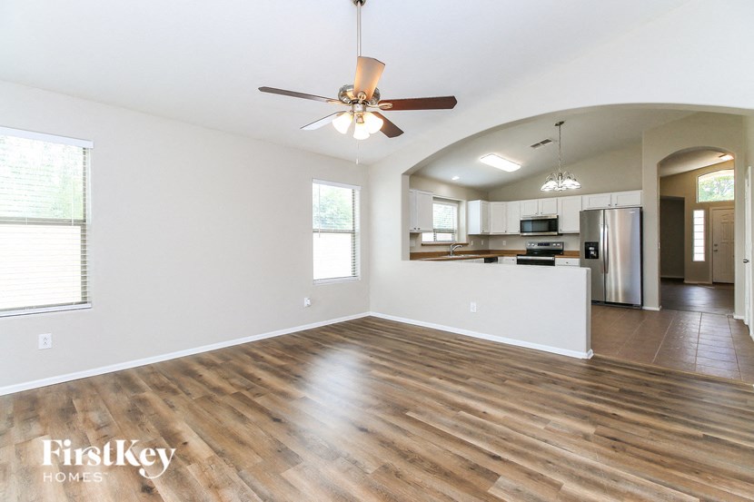 A spacious living room with a wooden floor and a ceiling fan.