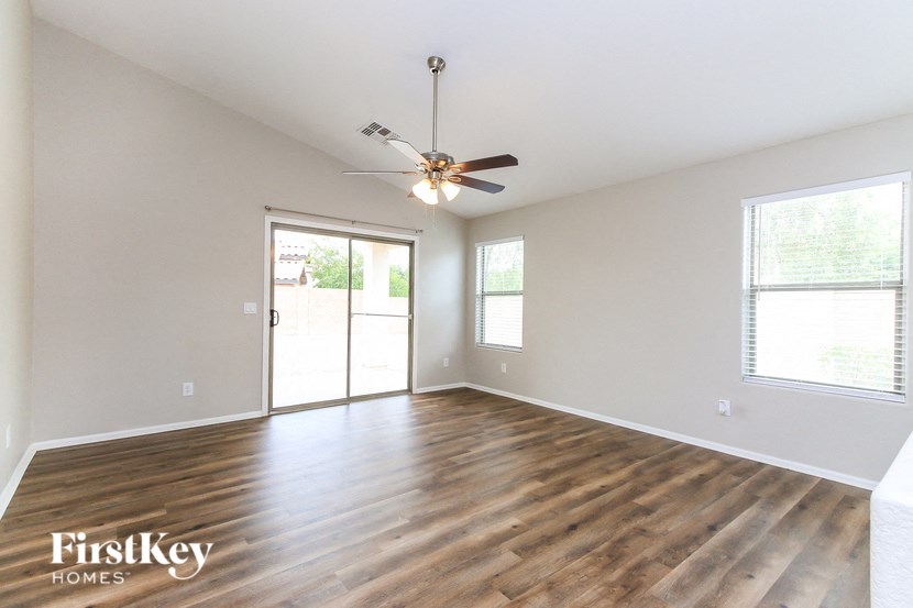A spacious room with wooden floors and a ceiling fan.