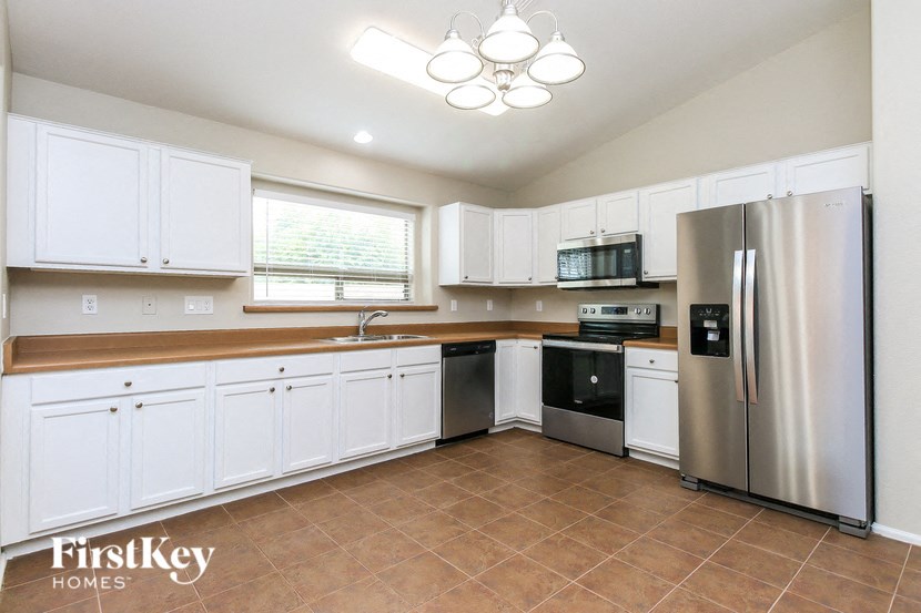 A kitchen with white cabinets and a stainless steel refrigerator.