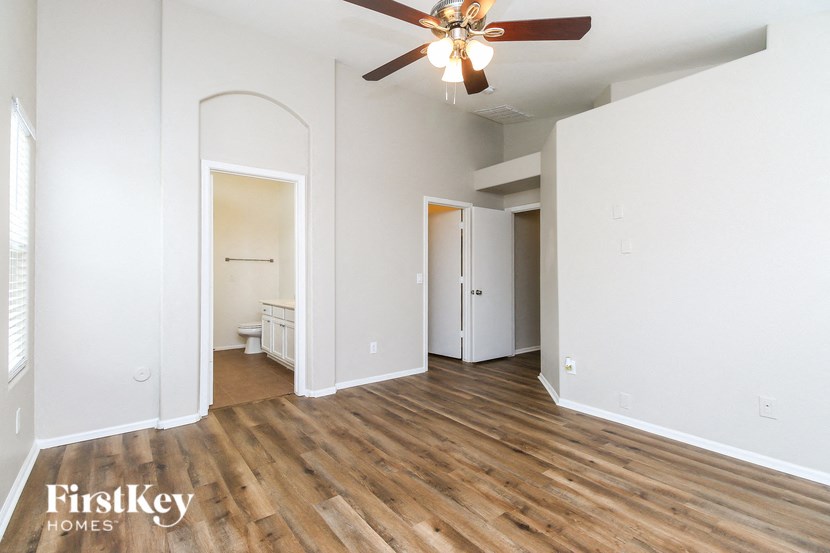 A spacious room with a ceiling fan and wooden flooring.