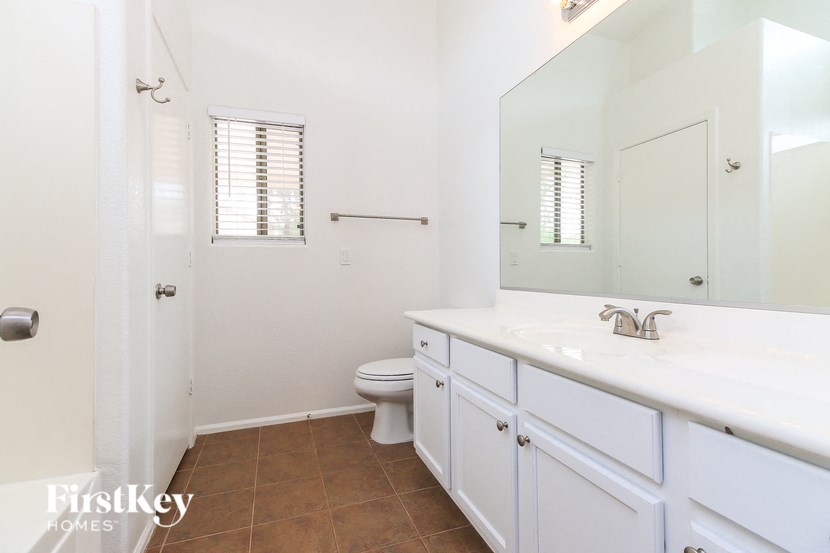 A white bathroom with a toilet, sink, and mirror.