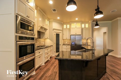 A modern kitchen with a black countertop and stainless steel appliances.