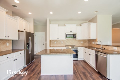 A kitchen with white cabinets and a brown island.