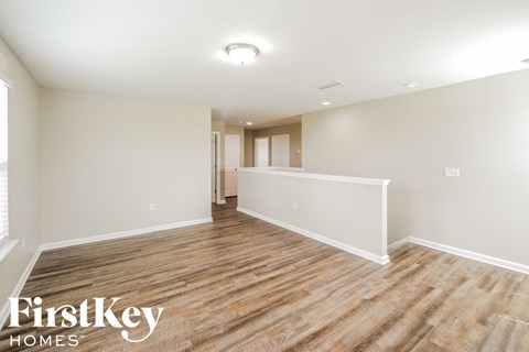 the living room and dining room with wood flooring and white walls