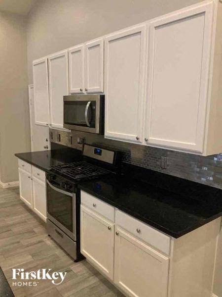 a kitchen with white cabinets and a stove and a microwave