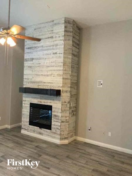 a stone fireplace in a living room with a ceiling fan