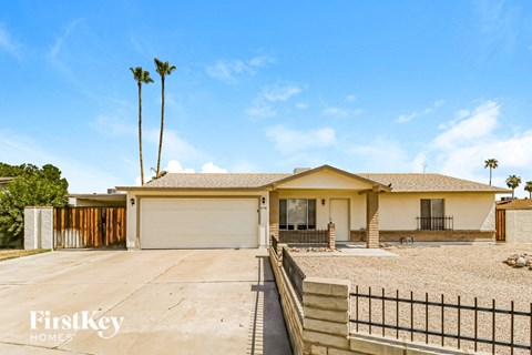 A house with a garage and a fence in front of it.