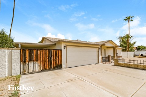 A house with a garage and a fence in front of it.