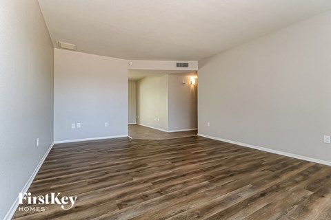 A spacious room with wooden flooring and white walls.