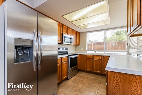A kitchen with a stainless steel refrigerator and wooden cabinets.