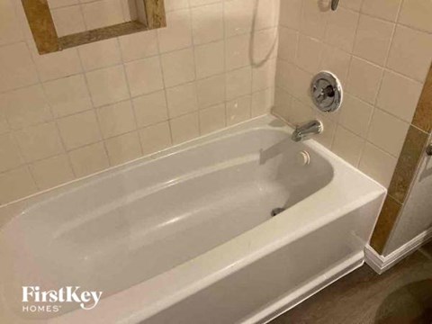a white bath tub in a white tiled bathroom