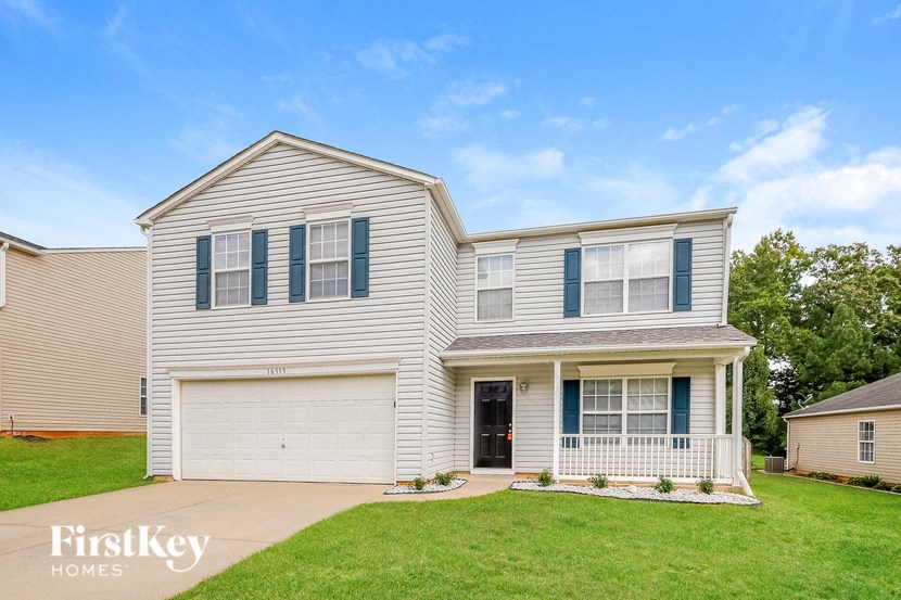 a white house with blue shutters and a green lawn