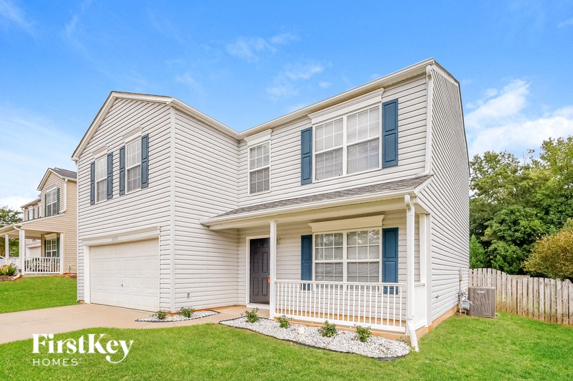 a white house with blue shutters and a lawn and a white fence