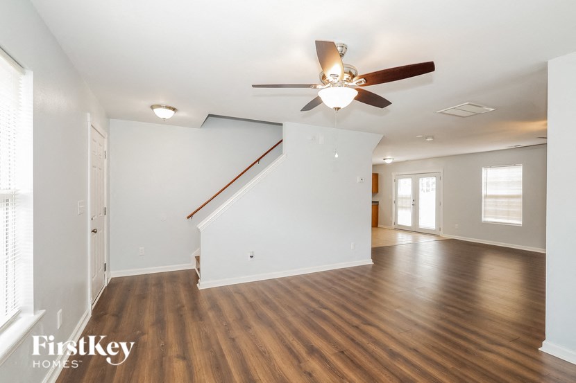 a living room with white walls and a ceiling fan