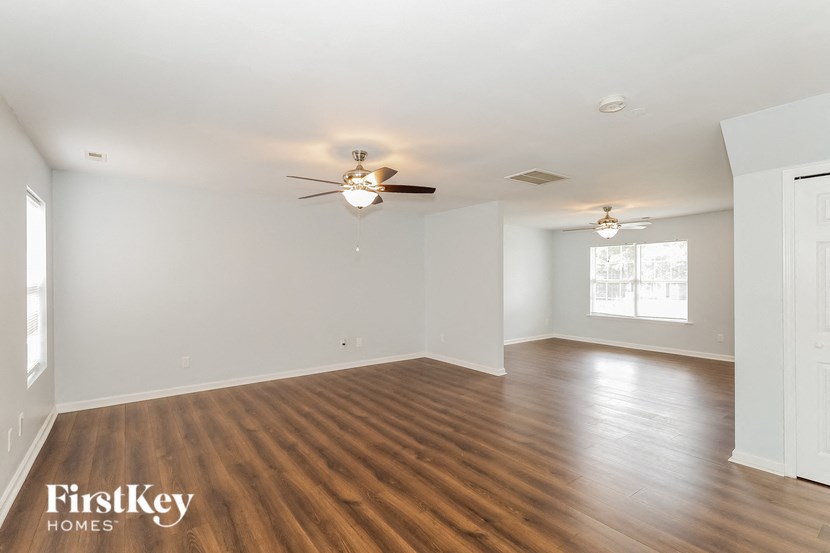 a living room with white walls and a ceiling fan