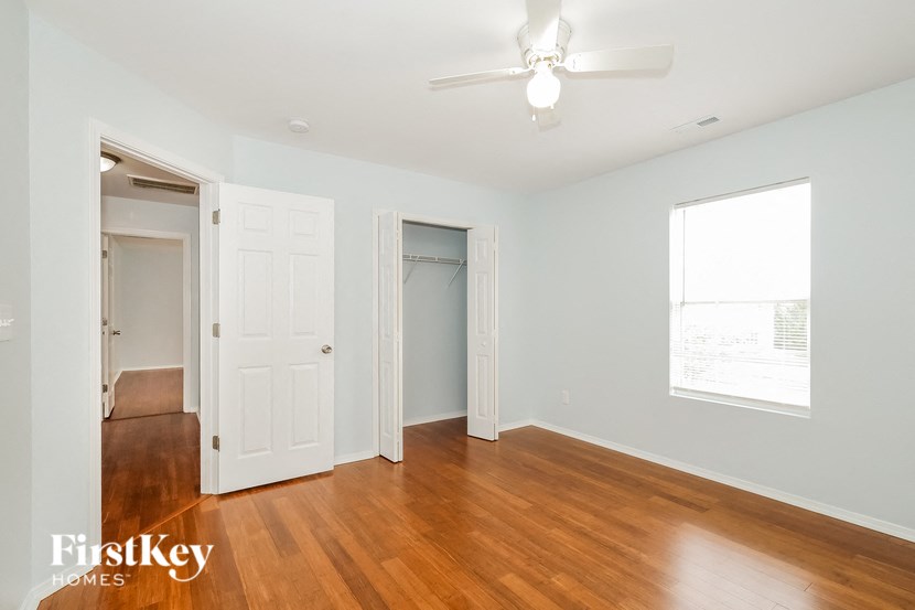 a bedroom with wood floors and a closet and a ceiling fan