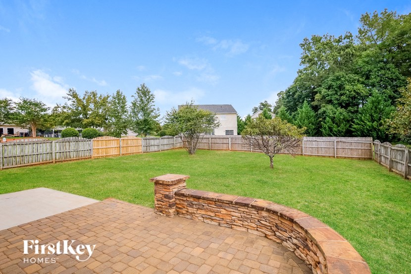 a backyard with a brick retaining wall and a lawn and a fence