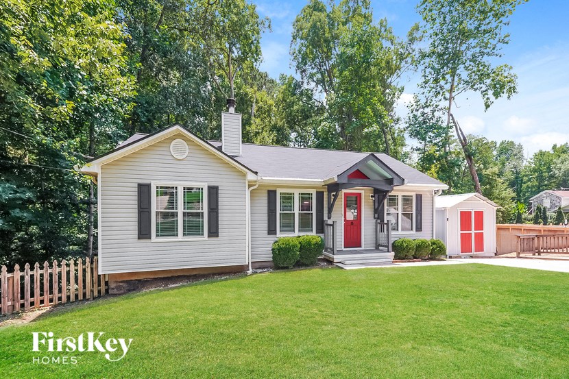a small white house with a red door and a yard