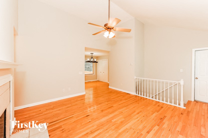 an empty living room with wood floors and a ceiling fan