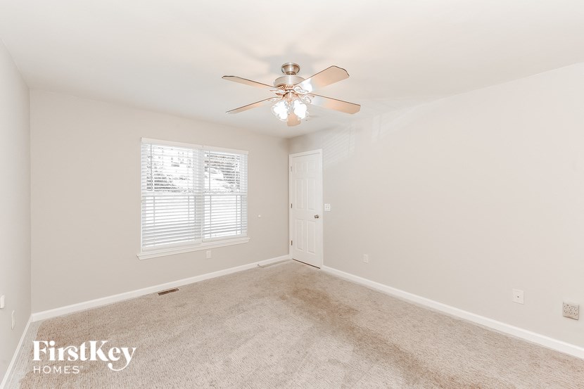 an empty bedroom with a ceiling fan and a window