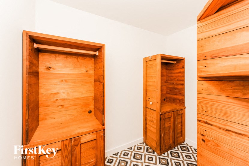 a walk in closet in a bedroom with wooden cabinets