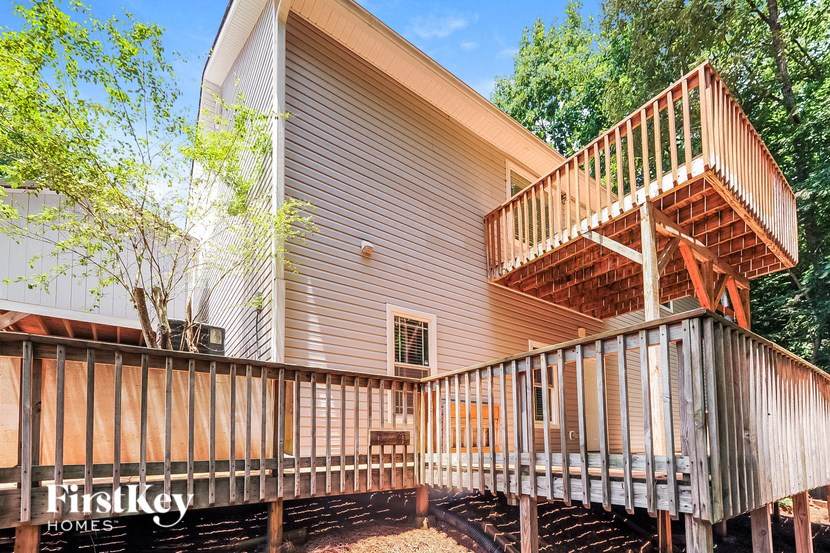 the back of a house with a deck and a wooden fence