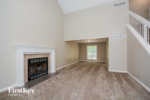 A spacious living room with a fireplace and carpeted floor.