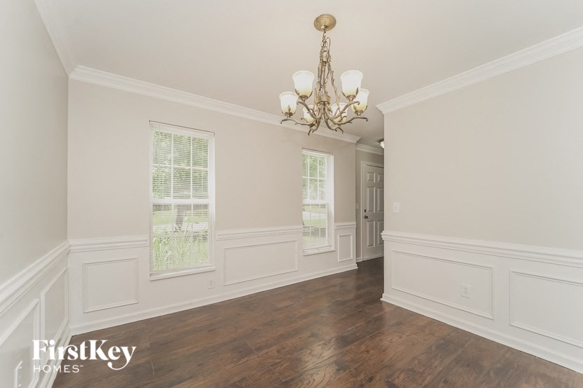 an empty dining room with white walls and a chandelier