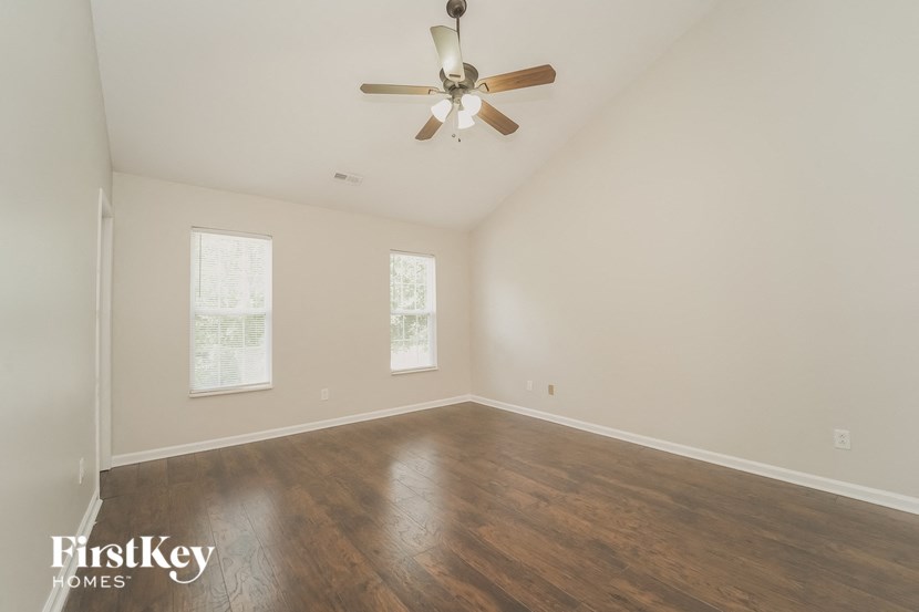 an empty living room with a ceiling fan and wood floors