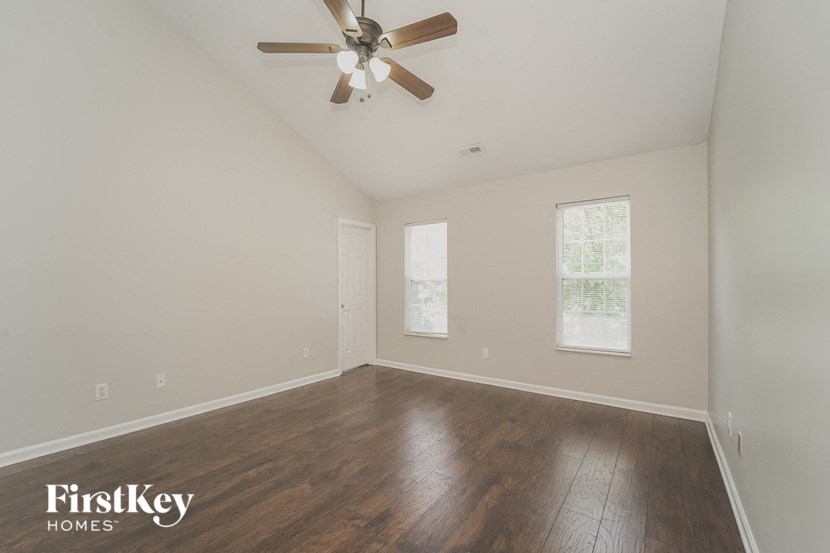 an empty living room with wood floors and a ceiling fan