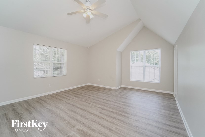 an empty living room with a ceiling fan and a window