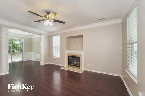 an empty living room with a fireplace and a ceiling fan
