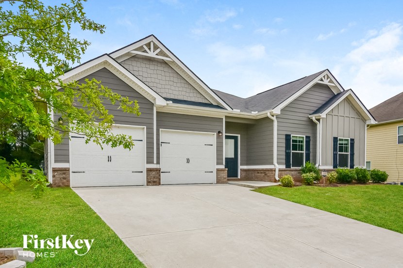 a gray house with white garage doors and a driveway