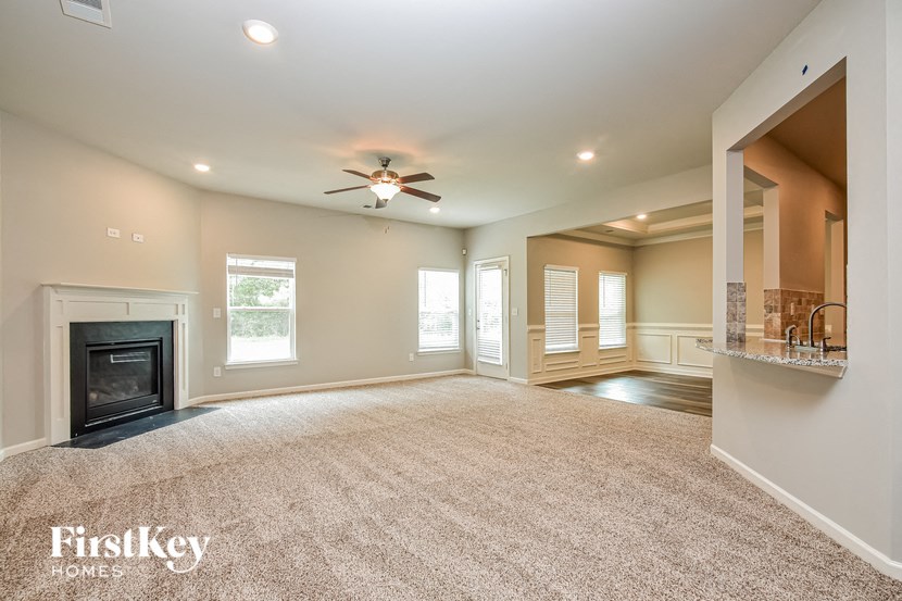 an empty living room with a fireplace and a ceiling fan
