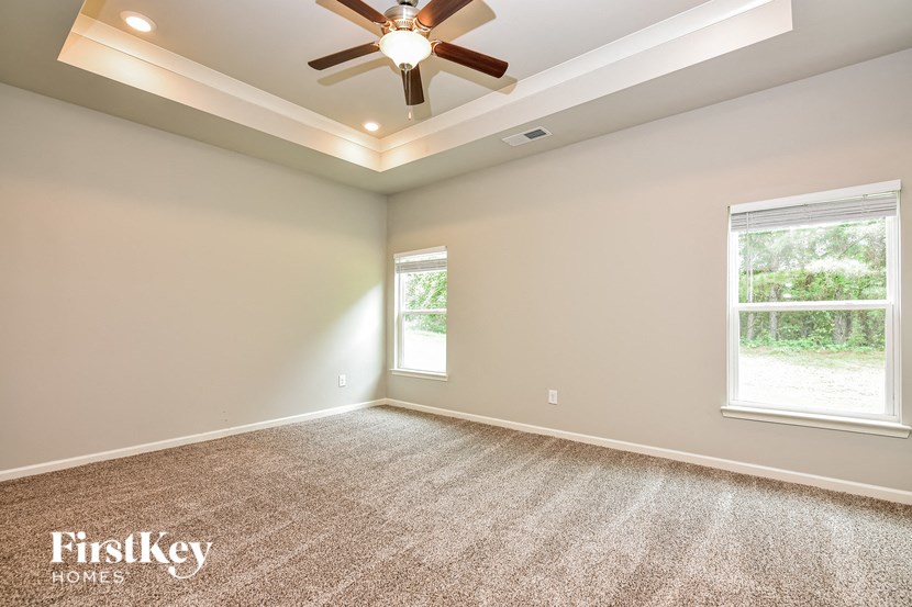 the master bedroom has a ceiling fan and a carpeted floor