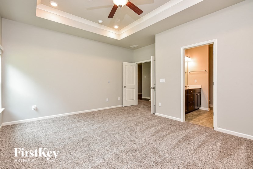 a spacious living room with carpet and a ceiling fan