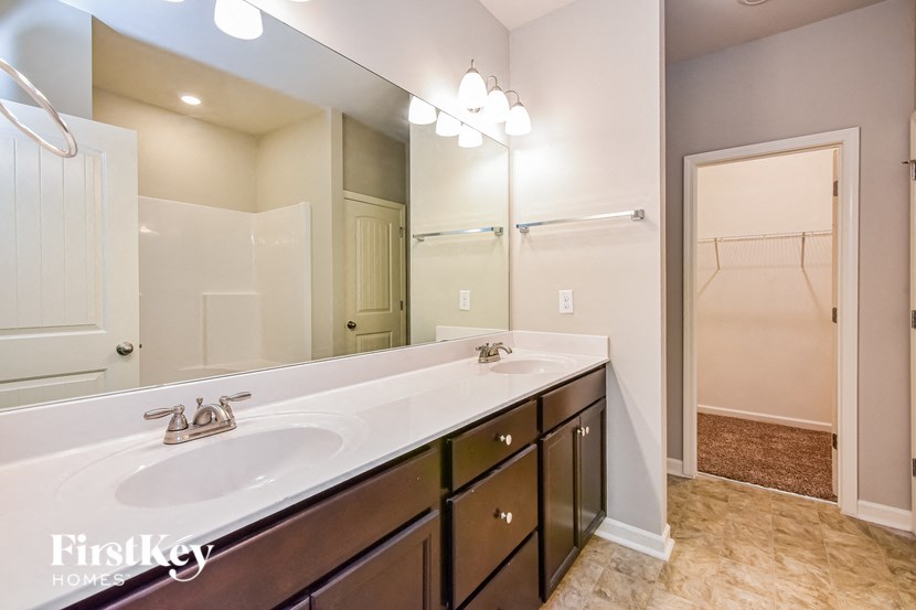 the master bathroom has a large vanity mirror and a shower