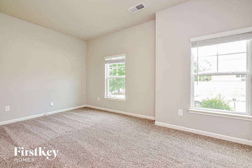 a bedroom with two windows and a carpeted floor